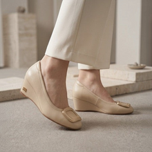 MOODBOARD beige leather wedge pumps with a decorative gold buckle detail worn with cream trousers.