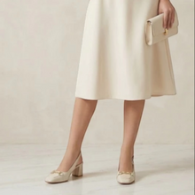 MOODBOARD Everbest beige leather slingback pumps with a gold-tone horsebit detail and block heel worn with a skirt.