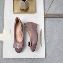 MOODBOARD Everbest mauve leather wedge pumps with a patent toe cap, bow detail, and gold hardware on a white surface.