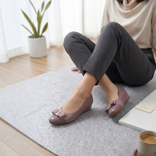 MOODBOARD Everbest mauve leather wedge pumps with a decorative bow detail worn by a woman sitting on a rug