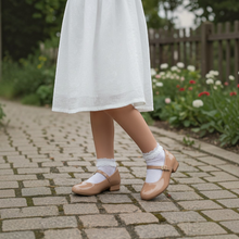 MOODBOARD Molekinha glossy beige Mary Jane shoes with buckle strap worn by a girl in a white skirt on a stone path